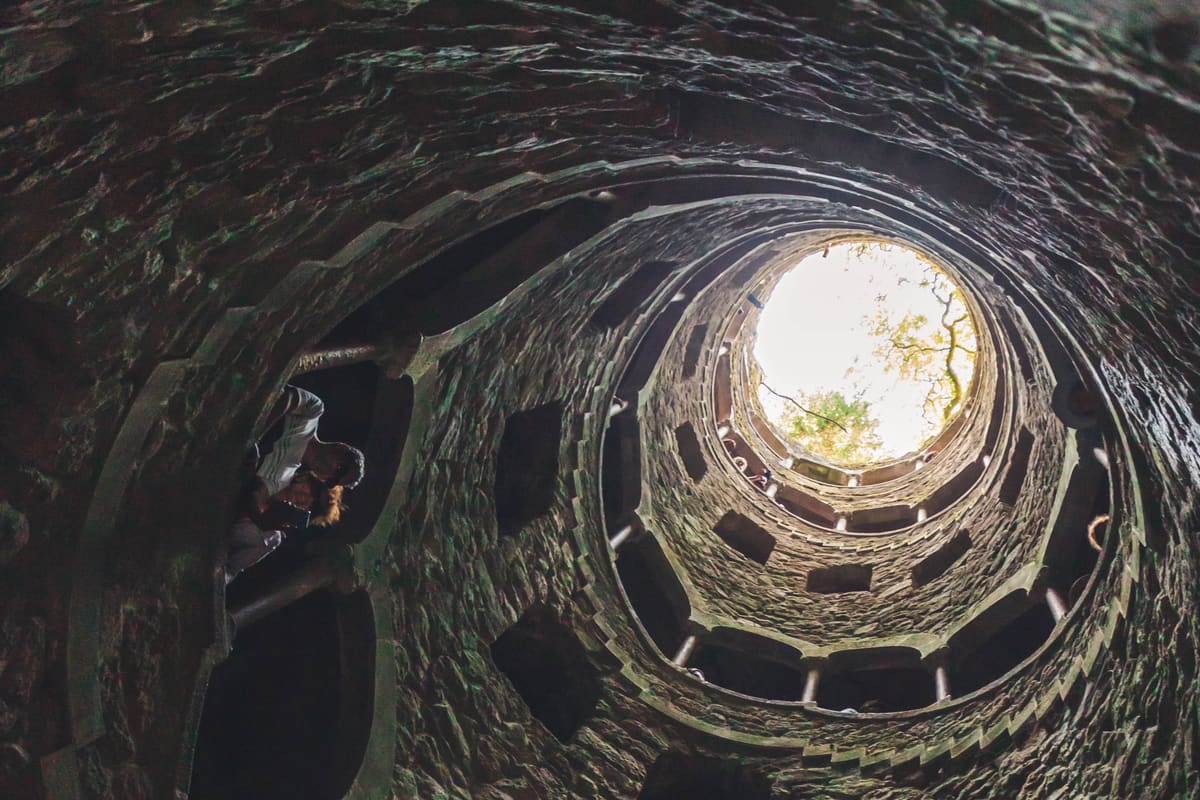 The Initiatic Well of Quinta da Regaleira — a 27-metre spiral staircase descending into the Masonic underground, viewed from below in Sintra, Portugal